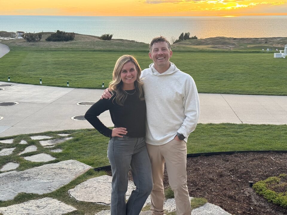 Jeff and Chelsea Musser standing together on a golf course at sunset